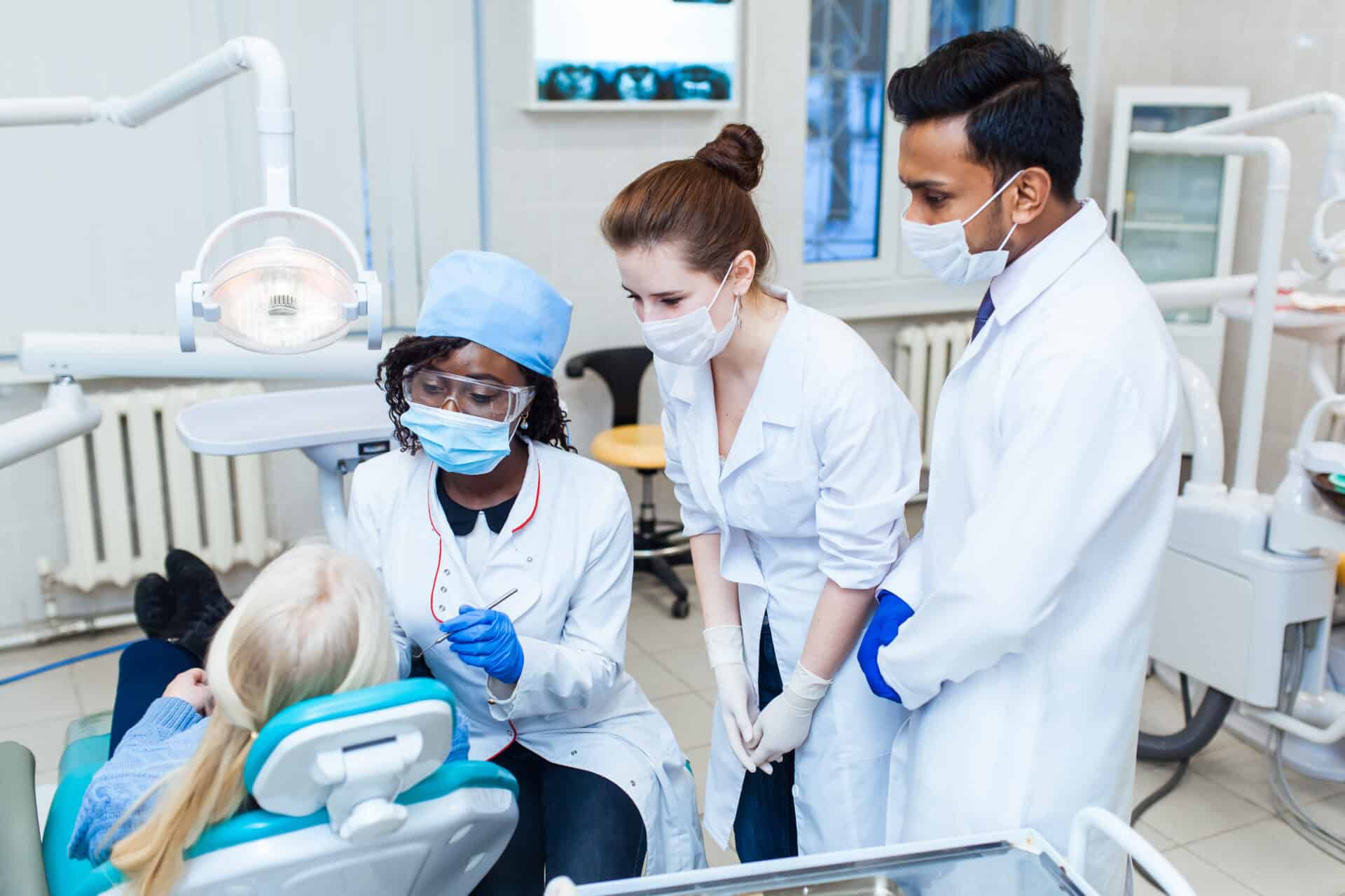 Health and healthcare. A multinational group of dentists examines x-rays in the presence of a patient. Practice at a medical university.